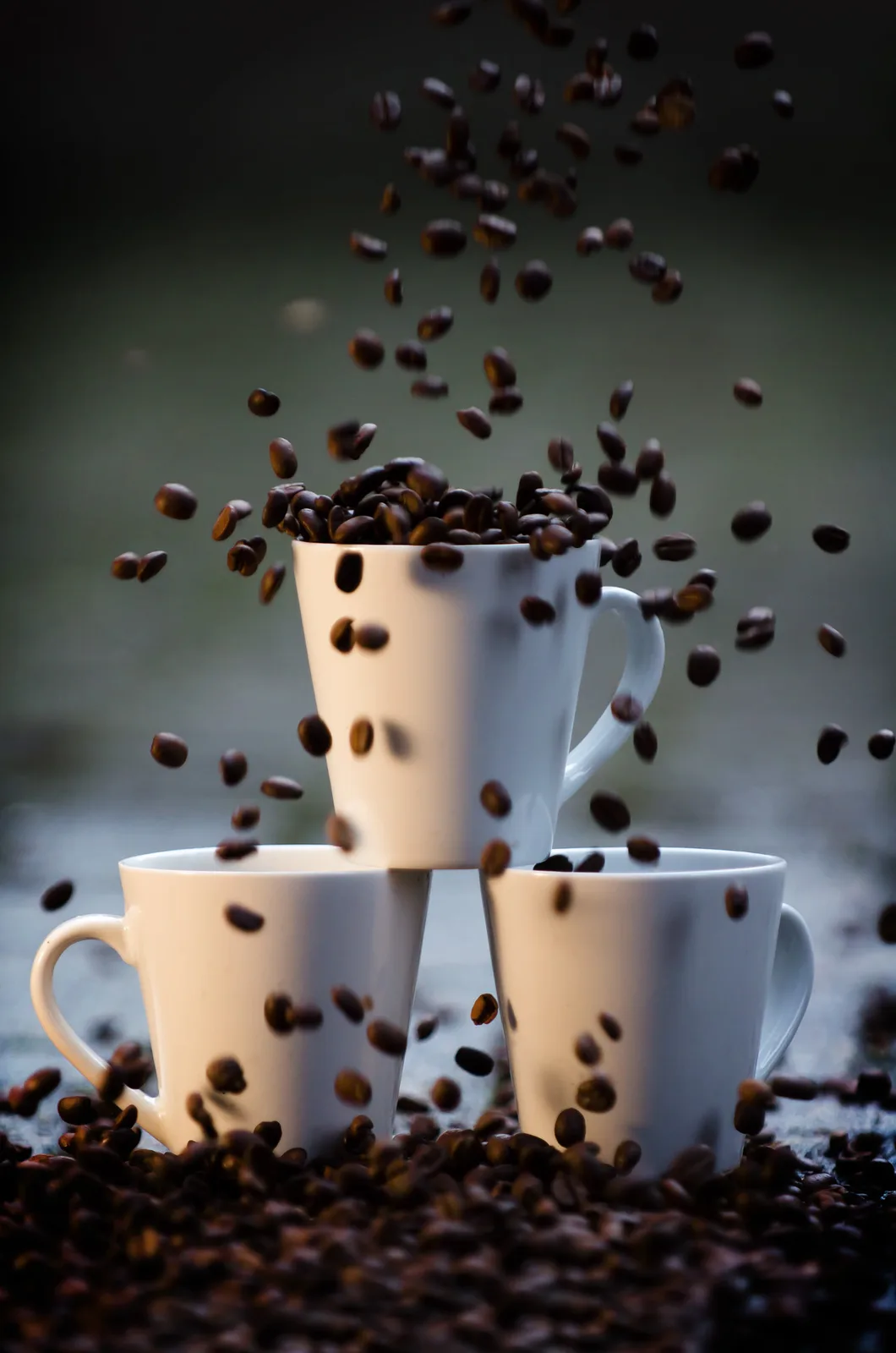 Koffiebonen vallen in drie gestapelde koffiekopjes
